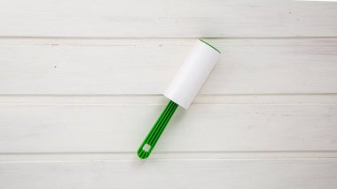 Beyaz ahşap arka planda toz, yün ve saç toplamak için yapışkan silindir