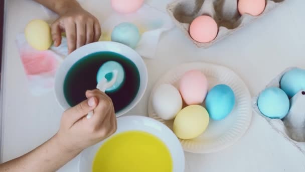 El primer plano de las manos de la muchacha para colorear huevos de Pascua sumergen en tinte verde líquido. — Vídeos de Stock