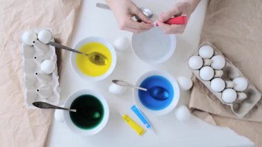 Paskalya yumurtalarını yumurta boyasıyla boyamak için ellerinizi yakın tutun. Yavaş çekim, 4k