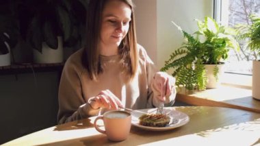 Evde avokado tostu yiyen genç bir kadın. Sağlıklı kahvaltı kavramı