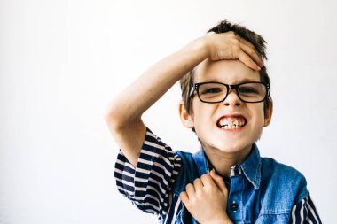 Otizm ve Görünmez Hastalık kavramı. Gözlüklü otistik çocuğun portresi beyaz bir duvarda asık suratlar..