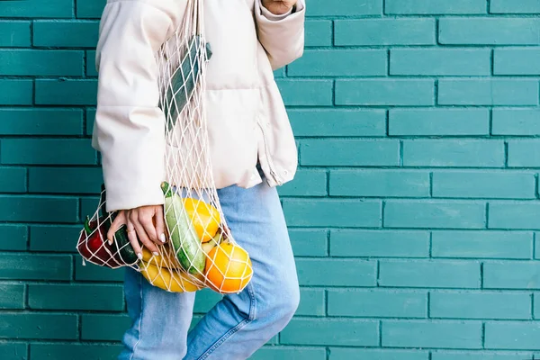 Concepto de cero residuos. Cerrar mujer sosteniendo bolsa de compras de malla reutilizable con frutas y verduras. Cerca de eco amigable comprador malla. Imagen De Stock