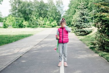 Çocuk paten kaymayı öğrenmeye çalışırken hatalara üzülüyor. Parkta kaykaydan düşen ağlayan küçük kız..