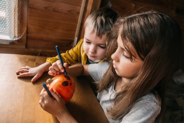 Cadılar Bayramı balkabağını evde boyayan çocukları kapatın. Kutlama evde hazırlanıyor.