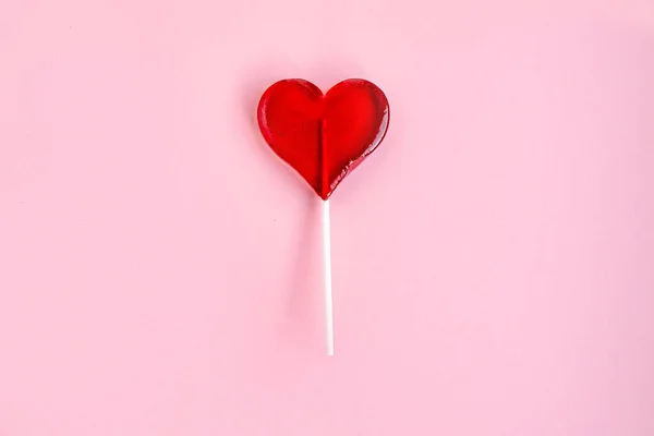 Piruleta roja en forma de corazón sobre fondo rosa Fotos De Stock