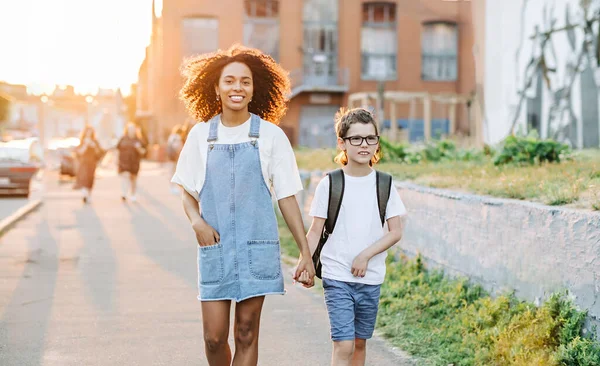 家庭教師と自閉症の少年は日の出に外の学校に戻って歩く。自閉症の子供と学校の概念に戻る ストックフォト