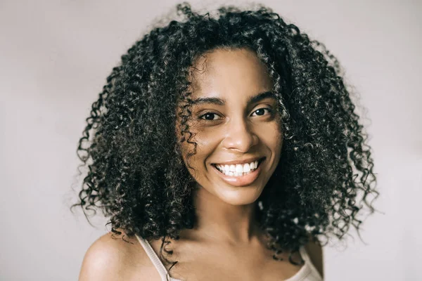 Beyaz arka planda gülümseyen güzel, kıvırcık Afrikalı Amerikalı genç bir kadının portresi. — Stok fotoğraf