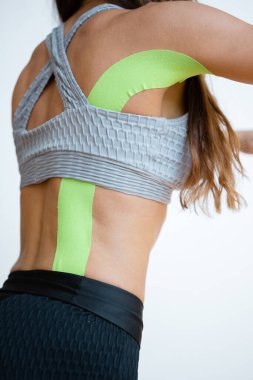 Arkadan bak. Sırtında Kinesio bandı olan bir kadın sporcu. Kinesio kayıt