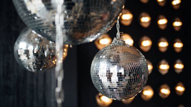 Ayna disko topları koyu gri duvarda asılı.