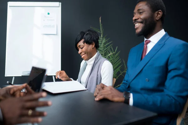 Dva šťastní obchodní partneři Afroameričané sedí u stolu v podkrovní kanceláři a podepisují dohodu o spolupráci — Stock fotografie