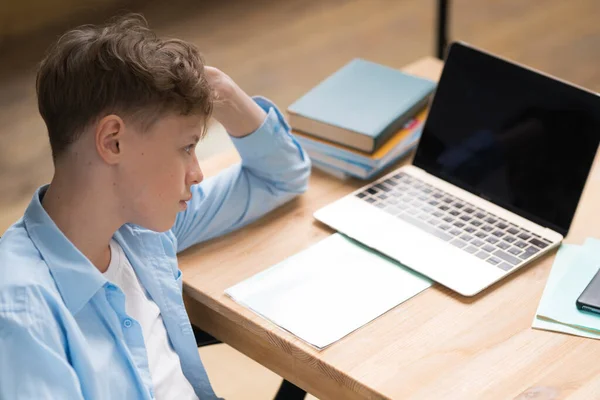 Mladý student se dívá na lekci online a studuje z domova. Mladý chlapec si dělá poznámky, zatímco se dívá na obrazovku počítače na videohovoru. Dívka studuje z domova na PC. — Stock fotografie