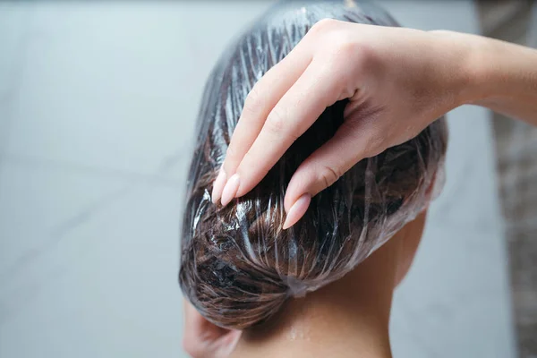 Vue de derrière. Femme met un bonnet de douche sur ses cheveux — Photo