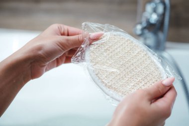 Kız köpük banyosunda oturur ve yeni bir duş süngeri ile bir kutu açar.