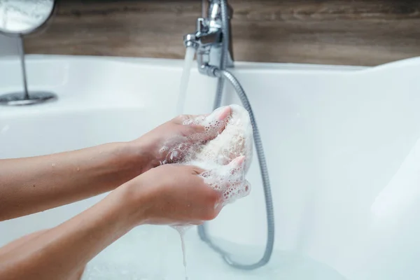 Primer plano de las manos femeninas con un paño. Mujer espumando un paño con gel para exuberante mientras está sentado en un baño — Foto de Stock