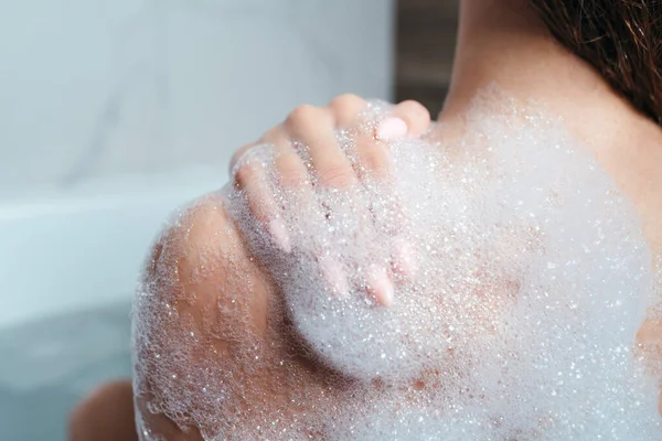 Primer plano de un hombro femenino en espuma. La chica se baña con espuma. Cuidado corporal, cuidado de la piel, procedimientos de espárragos — Foto de Stock