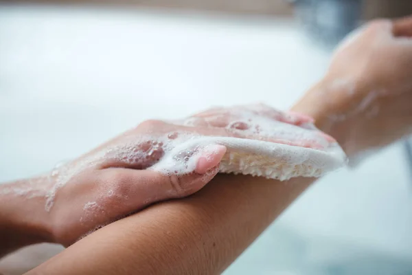 La chica toma un baño y lava su cuerpo con un paño para una ducha. Espuma de baño, gel de ducha, cuidado corporal — Foto de Stock