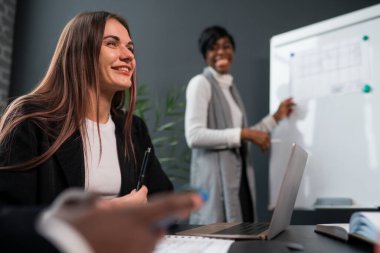 Afrika kökenli Amerikalı kadın öğretim görevlisi şirket işletme grafiği ile halka açık bir sunum yapıyor toplantı odasında beyaz yönetim kurulunda sonuç veriyor ve çok ırklı iş adamları dikkat çekiyor