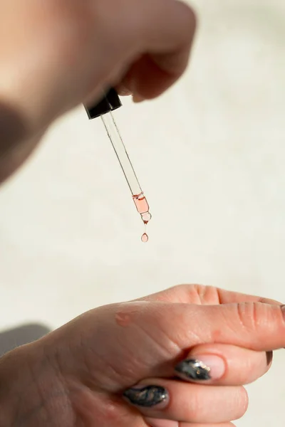 Close-up of a pipette with pink skin care serum.Macro photo of a drop of oil, skin care products.Cosmetology and skin care concept