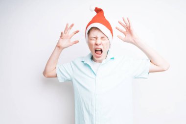 Beyaz arka planda, Noel Baba şapkalı beyaz bir çocuk çığlık atıyor.