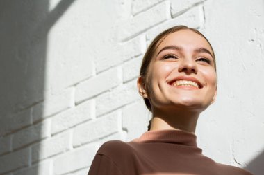 Alt manzara. Güzel, gülümseyen kız. Güneş ışığında hafif makyajlı mutlu bir kız. Makyaj, güzellik ve cilt bakımı kavramı