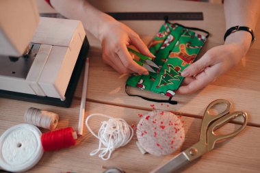 Terzi Coronavirus enfeksiyonu için yeni yıl maskesi yapıyor. Çocuğun komik maskesi ve Noel ağacı