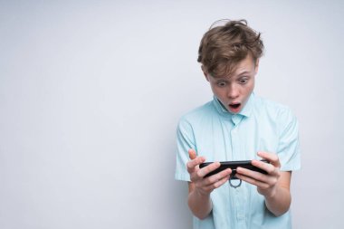 Beyaz bir çocuk telefondaki bir şeye şaşırmış gibi görünüyor.