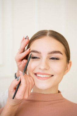 Güzellik konsepti. Doğal makyajlı güzel bir kızın portresi, sağlıklı parlak bir ten. Usta kaş makyajı yapıyor.