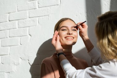 Bir usta güzel beyaz bir kız için kaş boyama yapar. Boyayla boyama, kaş makyajı. Kaş şekillendirme