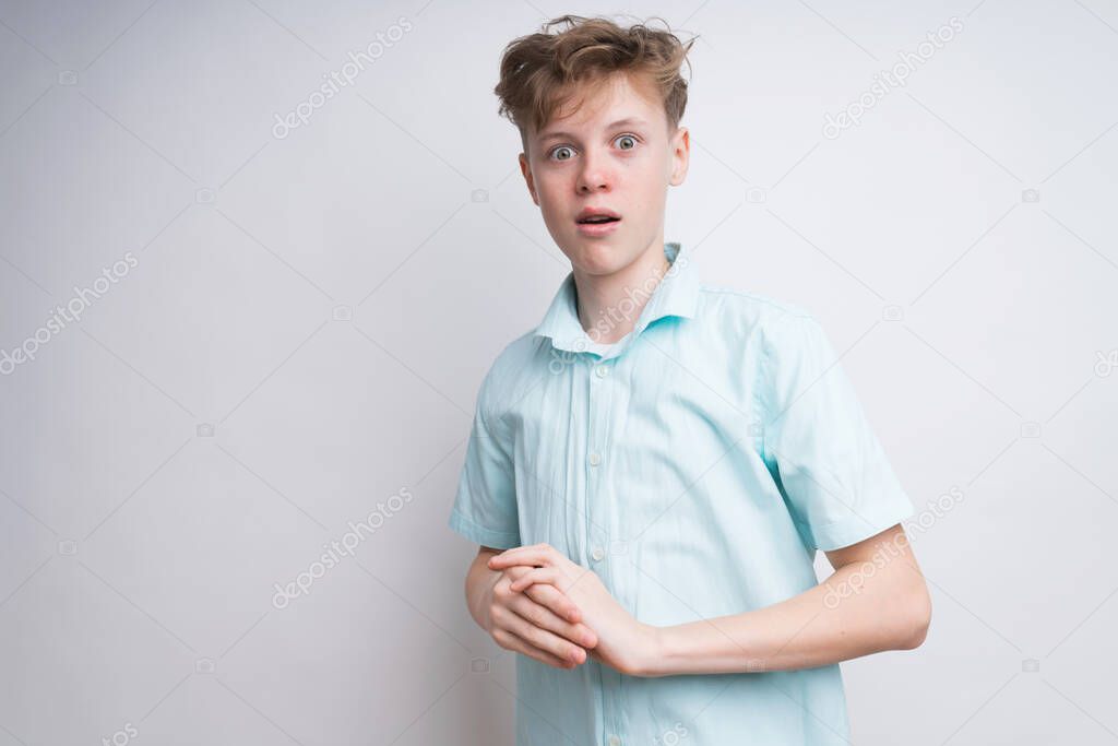 A Caucasian boy on a white background is amazed by something