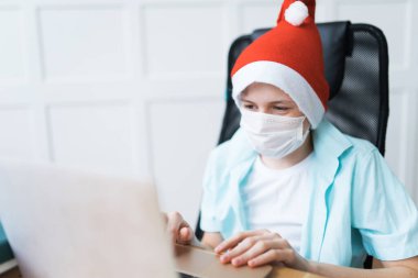 Tek kullanımlık yüz maskesi ve Noel Baba şapkası takan bir çocuk.