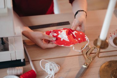 Ev yapımı Noel maskesi kadınların elinde. Koronavirüs enfeksiyonuna karşı koruyucu bir maskenin üst görüntüsü