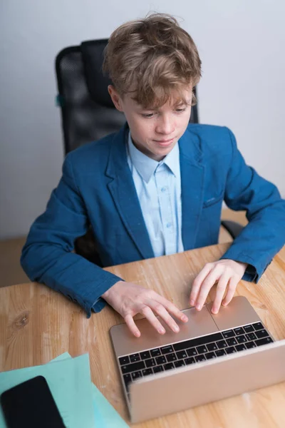 Um menino causaciano de uniforme escolar durante suas aulas on-line na quarentena — Fotografia de Stock