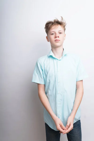 Um tiro médio de um menino adolescente caucasiano confiante bem parecido em uma camisa de pólo azul em um fundo branco — Fotografia de Stock