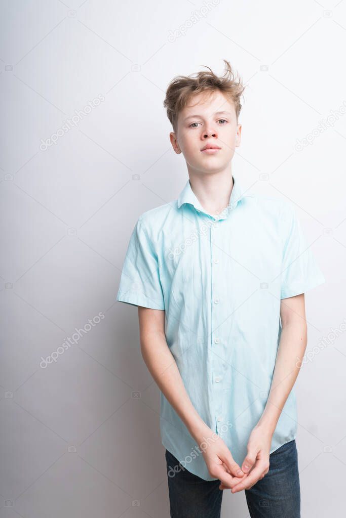 A mid shot of a good-looking confident Caucasian teenage boy in a blue polo shirt on a white background