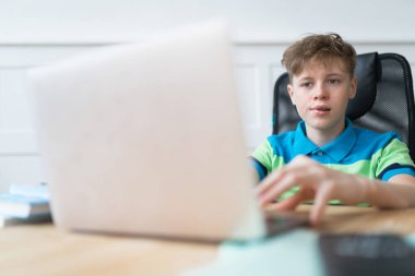 Beyaz tenli tatlı çocuk sınav sırasında gergin. Bilgisayarını kullanarak internetten ders çalışıyor. Çevrimiçi eğitim kavramı