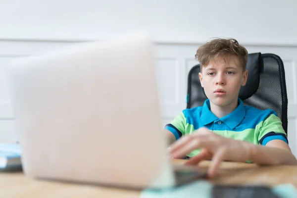 Rapaz pré-adolescente está estudando on-line via laptop, vídeo chamando seu professor. Ensino em casa, conceito de aprendizagem à distância — Fotografia de Stock