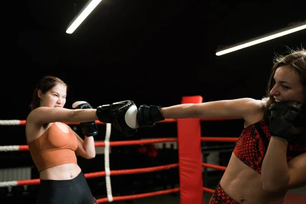 Duas pugilistas caucasianas lutam no ringue. Treinamento de boxe no ginásio — Fotografia de Stock