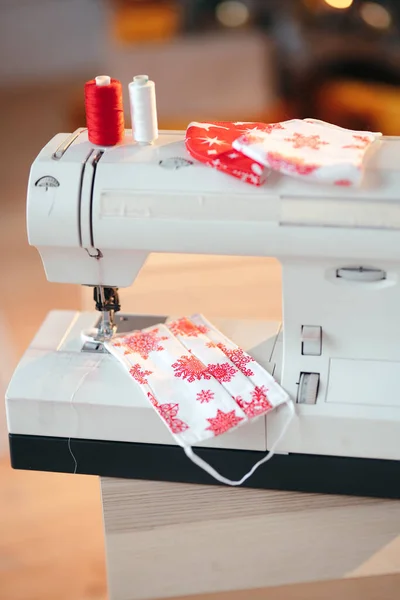 Eine Nahaufnahme aus Nähfäden, Nähmaschine und handgefertigten Weihnachtsgesichtsmasken aus Baumwolle. Weihnachtliches DIY und handgemachtes Konzept — Stockfoto