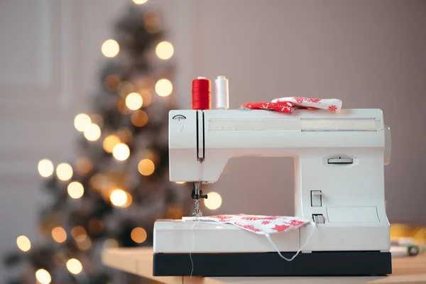 Ön planda atölye dikiş makinesi için Noel reklamı, arka planda şenlikli Noel ışıkları. — Stok fotoğraf