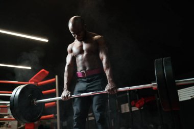 Spor salonunda halterle egzersiz yapan kaslı Afrikalı Amerikalı halterci ya da vücut geliştirici.
