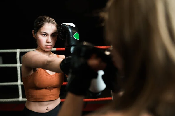 Mulher atlética forte em uniforme esportivo e luvas de boxe poderosas pretas durante a luta. conceito de boxe — Fotografia de Stock