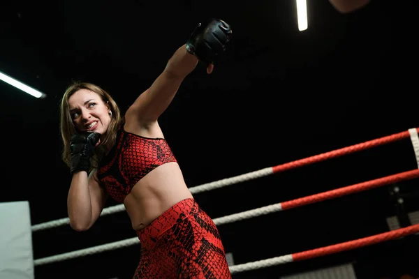 Mujer atlética fuerte en uniforme deportivo rojo y poderosos guantes de boxeo negros durante la pelea. concepto de boxeo —  Fotos de Stock