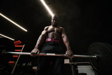 Bottom view. African american fitness trainer man doing exercises with a barbell on the trapezius muscles
