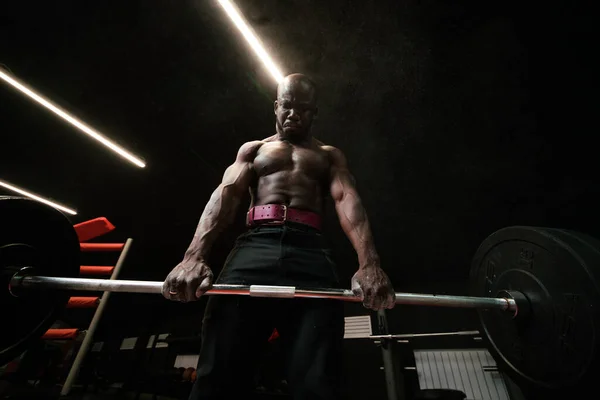 Spodní pohled. Afričtí američtí fitness trenér muž dělá cvičení s činkou na trapézových svalech — Stock fotografie