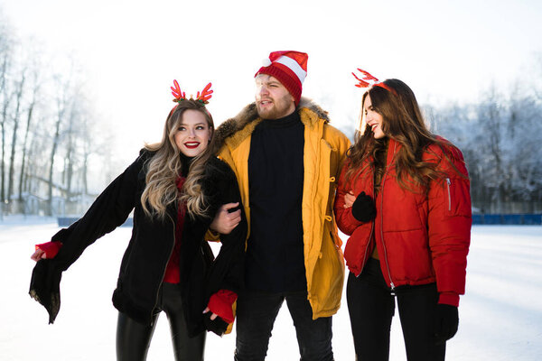 Мужчина держит двух девушек с рогами за локти, стоя на улице