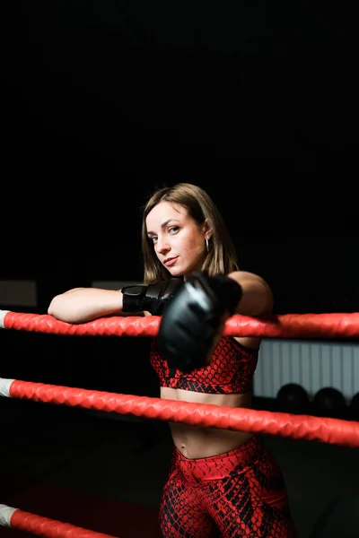 Menina sexy em luvas de boxe de um físico atlético fica no ringue no ginásio — Fotografia de Stock