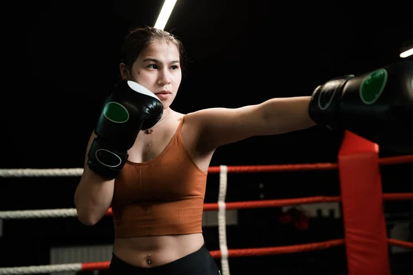 Mulher atlética forte em uniforme esportivo e preto poderosas luvas de boxe durante a luta — Fotografia de Stock