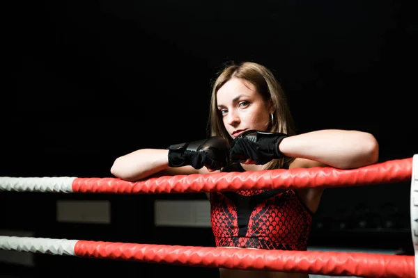 Menina sexy em luvas de boxe de um físico atlético fica no ringue no ginásio — Fotografia de Stock