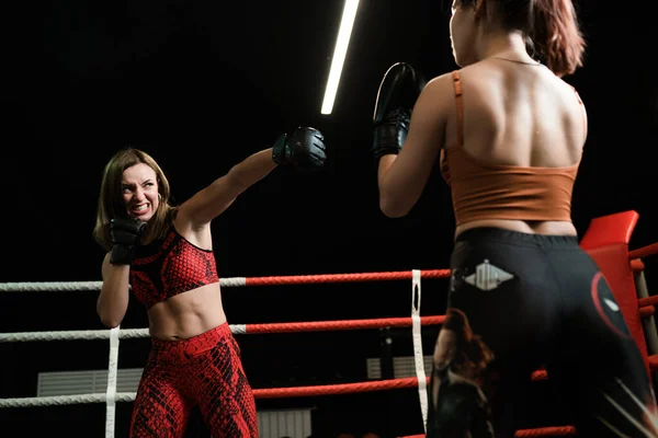 Sterke atletische vrouw in rood sportuniform en zwarte krachtige bokshandschoenen tijdens het gevecht. boksconcept. — Stockfoto