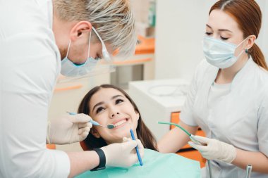 İki diş hekimi özel ekipman kullanarak hastadan parça alıyorlar.